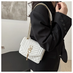 Close-up of a white quilted shoulder bag with a gold S-logo charm and chain strap