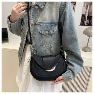 Detail of black crescent shoulder bag featuring a gold buckle and adjustable strap