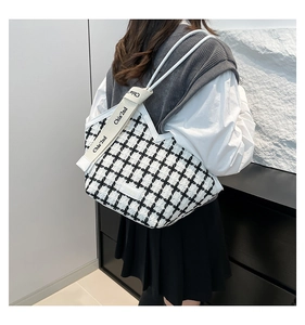 Side view of a black and white checkered tweed tote bag with stylish white handles