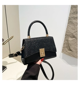 Dettaglio borsa nera con cuciture in paillettes e chiusura girevole quadrata dorata