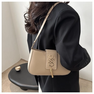 Close-up of beige crescent shoulder bag with metallic SSS logo and stylish fringe detail