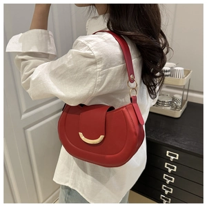 Red half-moon saddle bag with gold metal buckle shown on model in a stylish setting