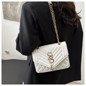 Detail of white quilted handbag with gold SS logo and elegant metal chain strap