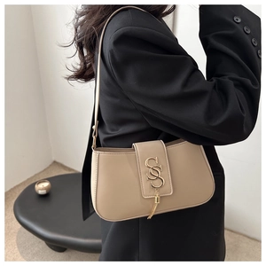 Khaki matte leather underarm bag with gold S-buckle and tassel on a stylish model