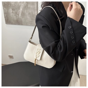 Close-up of cream square baguette bag with gold metal tassel buckle on a female model
