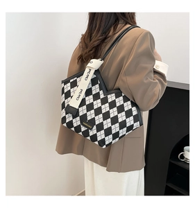 Detail of checkered tote bag with asymmetric top and decorative logo branding strap