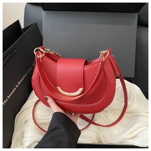 Detail of red crescent saddle bag with gold metal buckle and matching leather shoulder strap