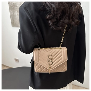 Detail of beige crossbody bag featuring V-quilt pattern and gold tassel chain strap