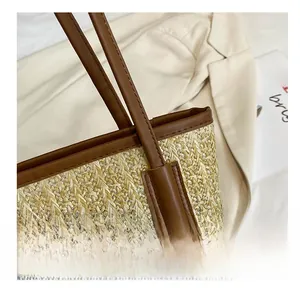 Detail shot of straw tote bag with reinforced brown leather handles and woven texture