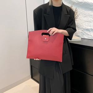 Minimalist red leather tote bag with cutout handles shown in an elegant fashion styling