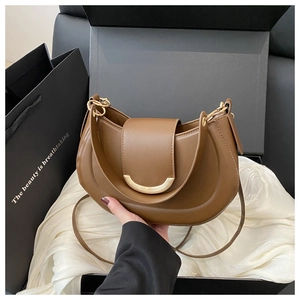 Close-up of a dark brown half-moon crossbody bag in a luxury black gift box with white silk