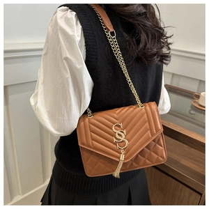 Detail of a brown quilted leather shoulder bag with gold SS logo and chain fringe tassel