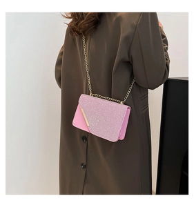 Detail of pink glitter crossbody bag with gold chain strap worn by a model