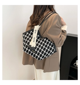 Detail view of black and white checkered tote bag with chic lettered ribbon and slim strap