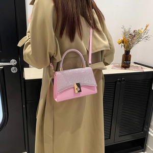 Borsa a tracolla rosa minimalista con fibbia dorata indossata da modella in trench