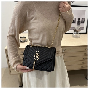 Detail of black quilted leather shoulder bag with gold metal tassel and chain strap