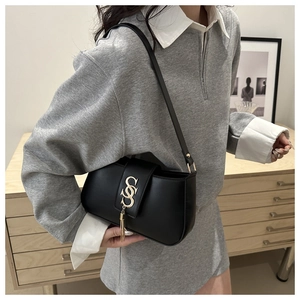 Side view of black square shoulder bag with gold S-shaped logo and elegant metal tassel