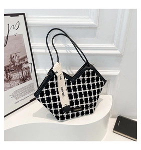 Detail of black and white tweed tote bag featuring V-shaped opening and woven tape