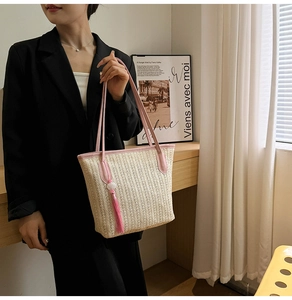 Detail of hand-woven straw tote with pink leather handles and beaded tassel charm