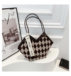 Detail of a vintage diamond-patterned tote bag with leather straps and decorative canvas strap