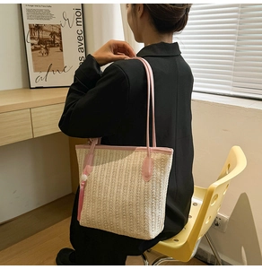 Straw tote bag with pink leather straps shown in a minimalist lifestyle setting