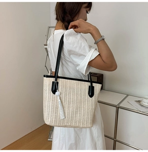 Detail of woven tote bag with white tassels and black PU leather strap for summer