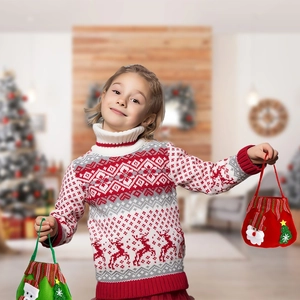 Child wearing reindeer sweater holding Santa and Christmas tree fabric gift bags in festive room