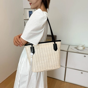 Fashionable large straw tote bag with black leather trim and tassel on female model
