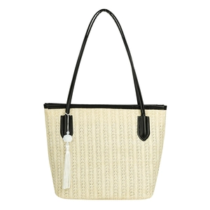 Handwoven straw tote bag with black leather straps and decorative white tassel pendant