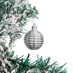Silver Christmas ball ornament with horizontal stripes hanging on a snowy tree branch