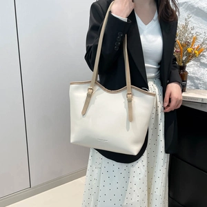 Minimalist white leather tote bag with brown straps shown on a model in a modern room