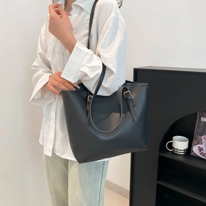 Minimalist black leather tote bag with adjustable straps and gold buckles for women