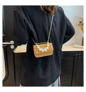 Detail of khaki crocodile pattern bag with pearl handle and golden chain on a model