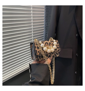 Close-up of leopard print handbag with pearl handle and golden chain strap detail