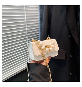 Detail of white faux leather mini bag with crocodile texture and pearl buckle accent
