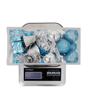 32-piece blue and silver Christmas ornament set on a digital scale showing 100g weight