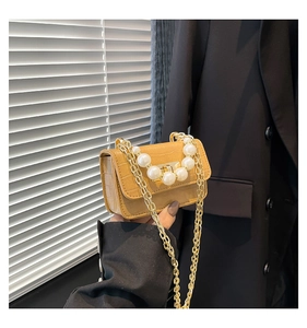 Detail of yellow crocodile pattern mini flap bag with luxury pearl handle and gold chain