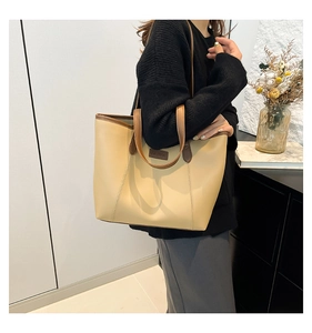 Détail du sac cabas beige minimaliste avec bordure marron porté par un mannequin