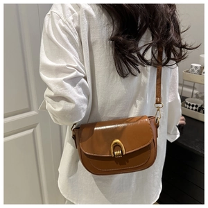 Caramel brown saddle bag with golden buckle detail shown on a model in a side view