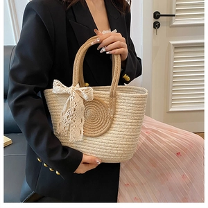 Texture détaillée d'un sac cabas en paille tissé main avec nœud en dentelle blanche
