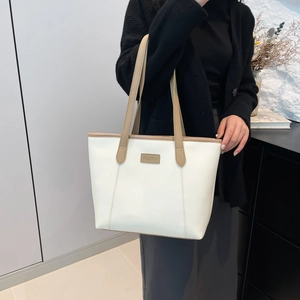Elegant white and tan faux leather tote bag showcased by a model in a minimalist room