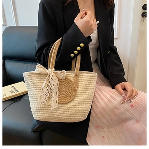 Détail du sac cabas en paille tressée avec nœud en dentelle blanche et texture douce