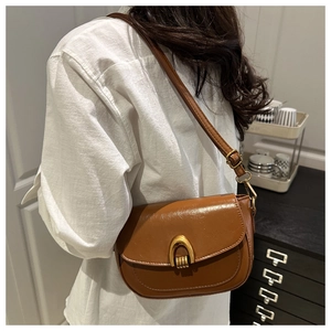 Detailed view of the brown vintage saddle bag with gold horseshoe buckle on shoulder