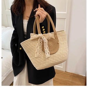 Détail du sac cabas en paille tissée avec bordure en spirale brune et nœud en dentelle