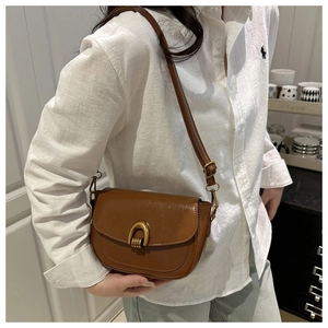 Brown vintage leather shoulder bag featuring a unique gold horseshoe buckle and strap