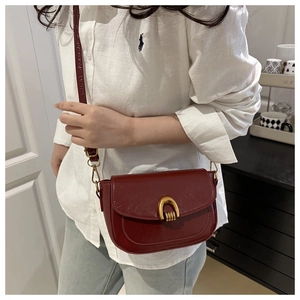 Detail of vintage burgundy leather saddle bag with horse-bit gold buckle and shoulder strap