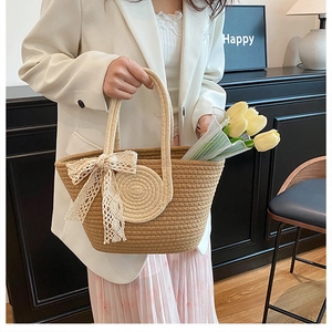 Détail d'un sac cabas en paille tressée avec un nœud en dentelle beige et texture naturelle