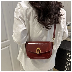 Detail of burgundy vintage crossbody bag with gold U-shaped metal buckle on model