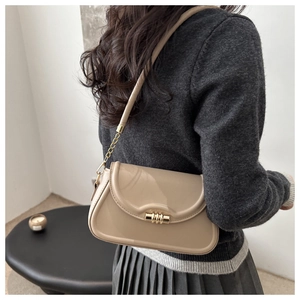Detail view of beige patent leather shoulder bag with gold twist lock and chain strap