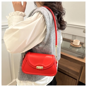 Detail of red faux leather shoulder bag with spiral gold buckle and chain strap